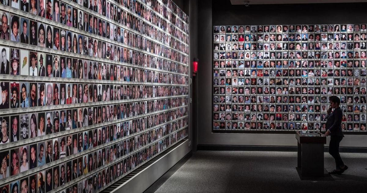 A woman visits the In Memoriam exhibition. On the wall in front of her and to her right are 2,983 portrait photographs of the victims.