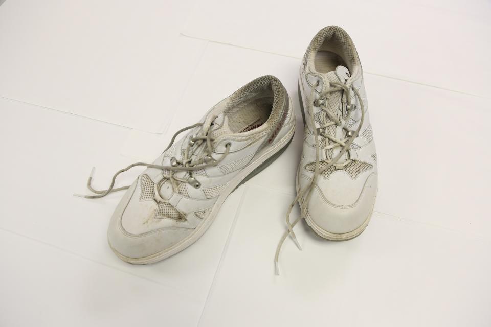 A pair of white sneakers worn by George Martin during his walk across the country is displayed on a white surface.
