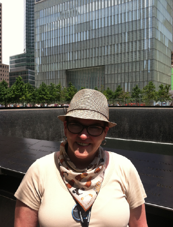 Volunteer Eileen Egan-Annechino smiles beside a reflecting pool on Memorial plaza on her first day of docent training. One World Trade Center is visible in the background.