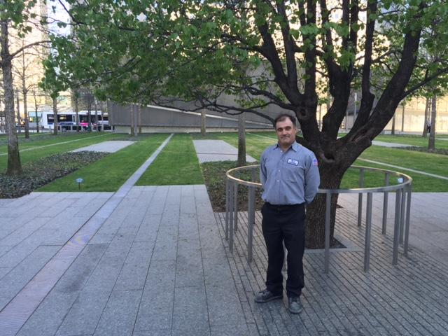 9/11 Memorial mechanic Jose Mendes poses for a photo next to the Survivor Tree on Memorial plaza.