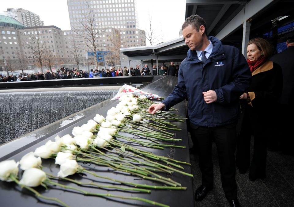 9/11 Memorial President Joe Daniels places a white rose amid a row of white roses on a bronze parapett at the memorial. 9/11 Memorial Museum Director Alice Greenwald is seen behind him.