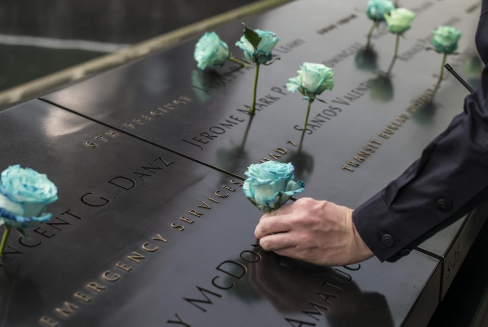 An NYPD officer places a blue rose at a name on the 9/11 Memorial during National Police Week.