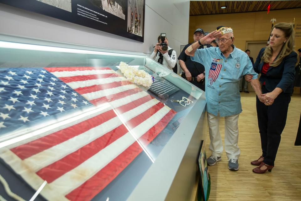 John Seelie, a U.S. Army veteran and Pearl Harbor survivor, salutes an American flag that flew at Ground Zero as he stands beside it at the 9/11 Memorial Museum.