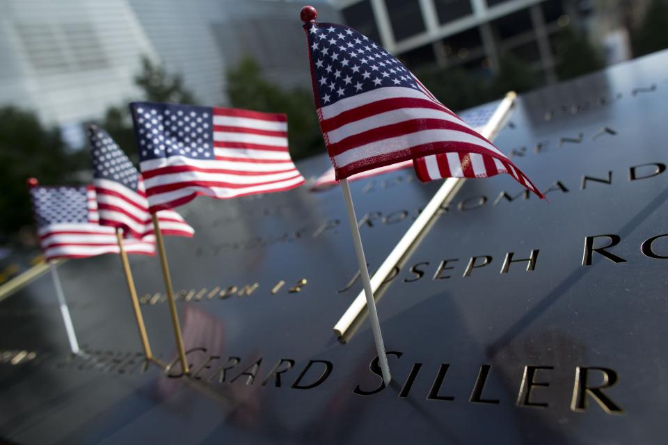 Several small American flags stand at the name of firefighter Stephen Gerard Siller on a bronze parapet at the 9/11 Memorial.