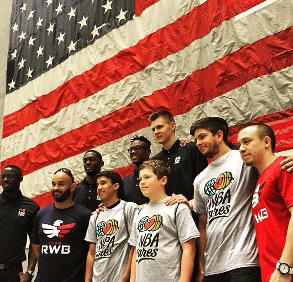 Tuesday’s Children participants pose with NBA draft prospects in front of the national 9/11 flag at the 9/11 Memorial Museum.