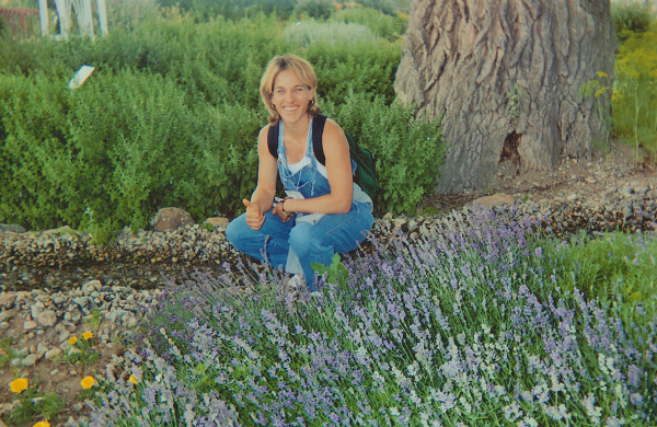 Jennifer Louise Fialko gives a thumbs up as she poses for a photo in a flower garden.