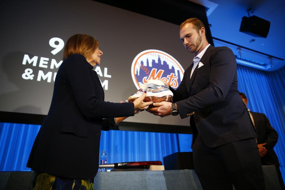 Mets first baseman Pete Alonso hands his 9/11 tribute cleats to 9/11 Memorial & Museum President and CEO Alice M. Greenwald onstage at the Museum auditorium.