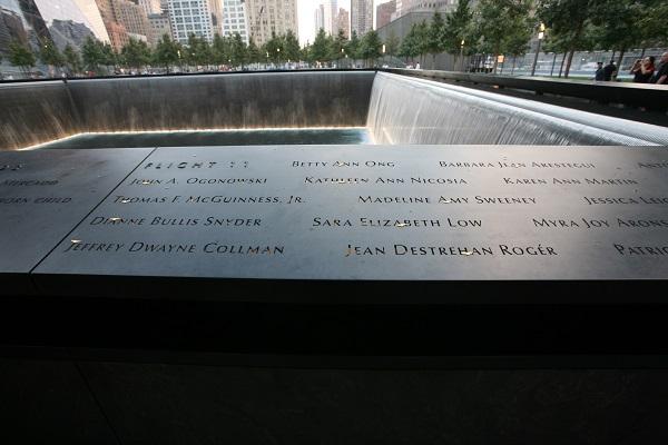 The names of the victims aboard Flight 11 are seen etched in a corner of the Memorial. Water cascades down the sites of a reflecting pool behind the names.