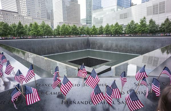 Dozens of small, American flags have been placed at names on the 9/11 Memorial in a sweeping photo of the south pool.