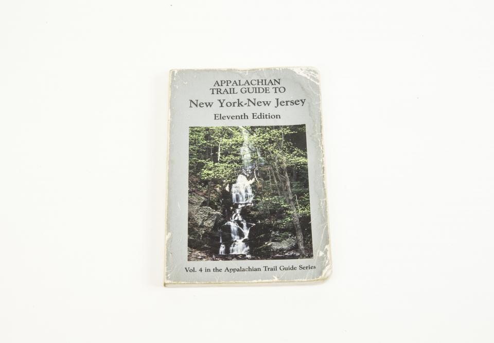 An Appalachian trail guidebook belonging to Bruce Van Hine is displayed on a white surface. The book includes a cover image of a waterfall.
