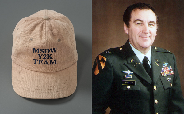 A tan Morgan Stanley “Y2K Team” hat that belonged to Cantor Fitzgerald employee Nicholas Craig Lassman is displayed on a gray surface. Richard Cyril Rescorla, director of security for the financial services firm Morgan Stanley, poses in a formal military uniform for an official photo.