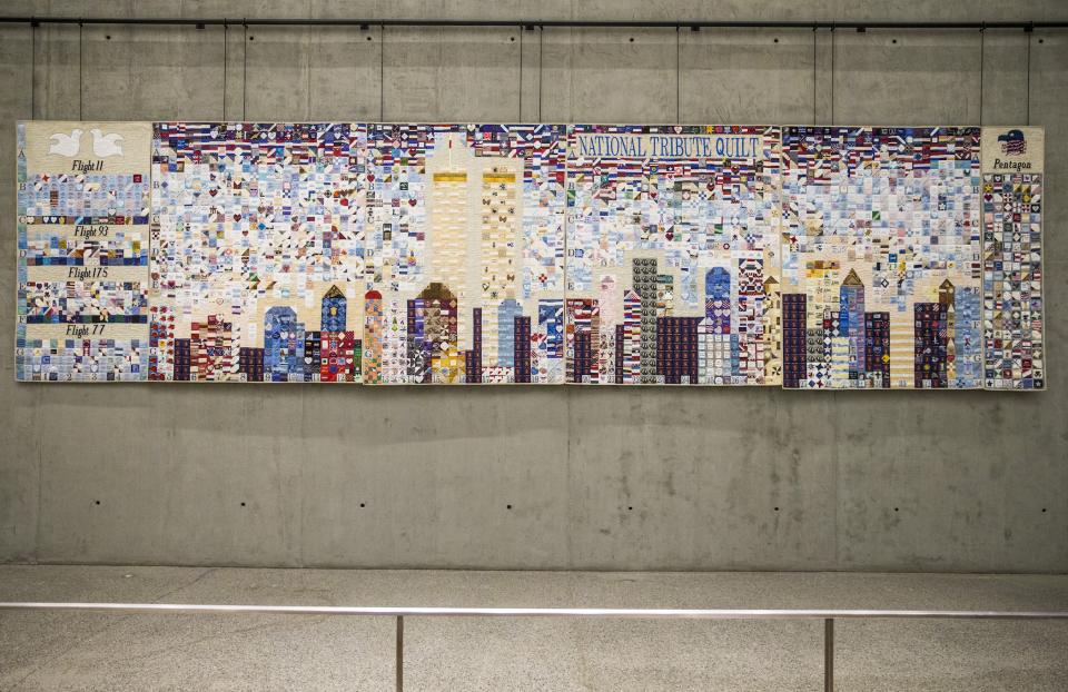 The National Tribute Quilt hangs in the 9/11 Memorial Museum’s Tribute Walk. The quilt depicts the New York City skyline, including the Twin Towers.