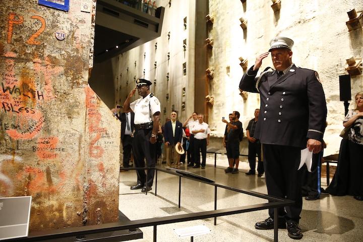 FDNY and NYPD rescue and recovery workers salute the Last Column in the Museum’s Foundation Hall. Messages written on the column can be seen in the foreground.