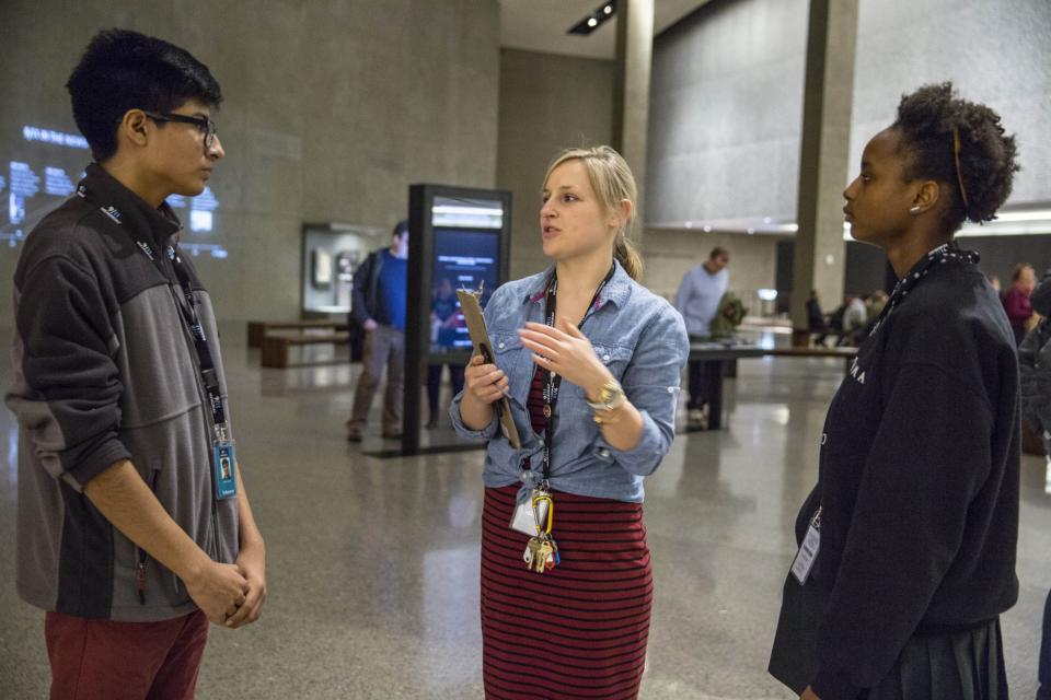 Education specialist Emily Stupfel stands with a young man and young woman who are part of the ambassador program in Foundation Hall.