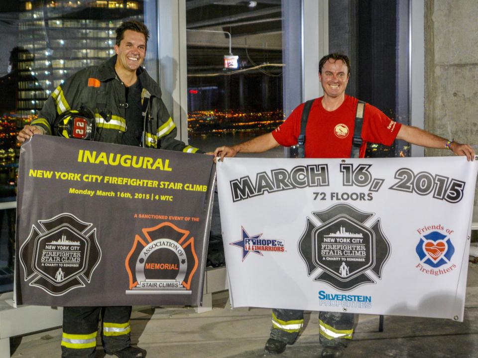 Firefighters Chris Barber and John Mills hold up flags of the New York City Firefighter Stair Climb.