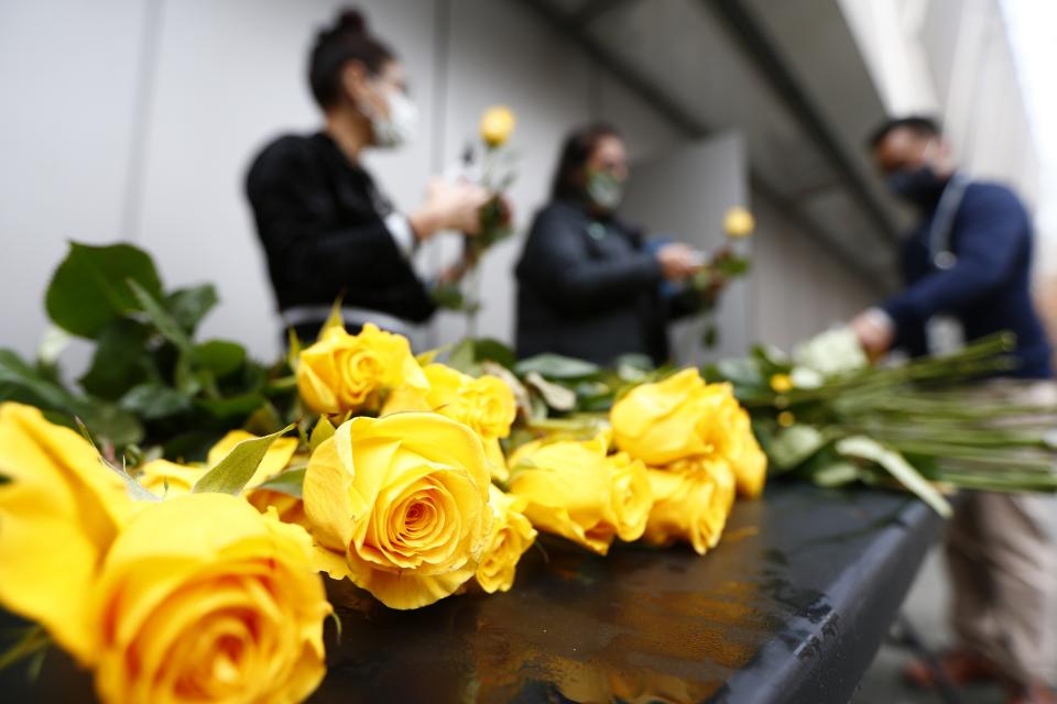 Volunteers prep yellow roses for Veterans Day placement on the Memorial